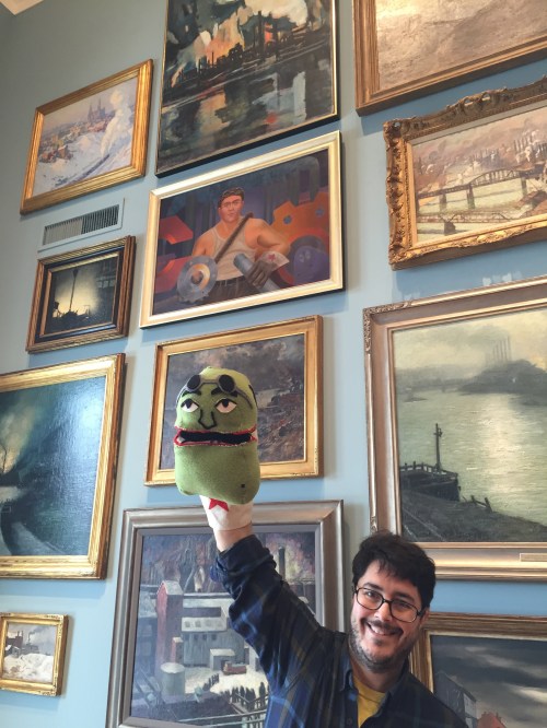 Mike Cuccaro with Mike Kessel puppet, under the Portrait of Mike Kessel. 
